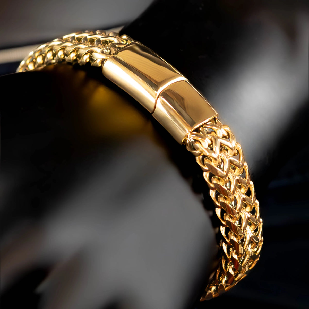 Gold chain bracelet with a smooth central bar connecting the intricate links.