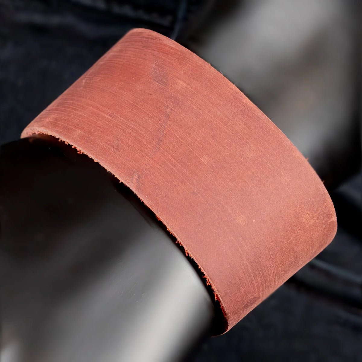 Curved piece of reddish-pink sandpaper or abrasive material.