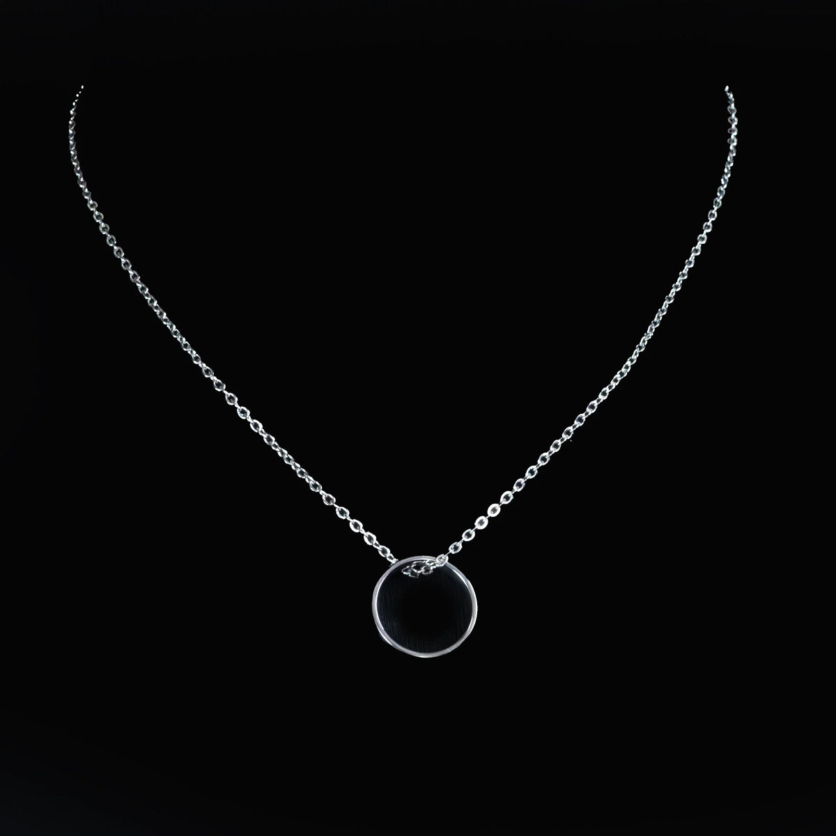 Silver necklace with a circular pendant.