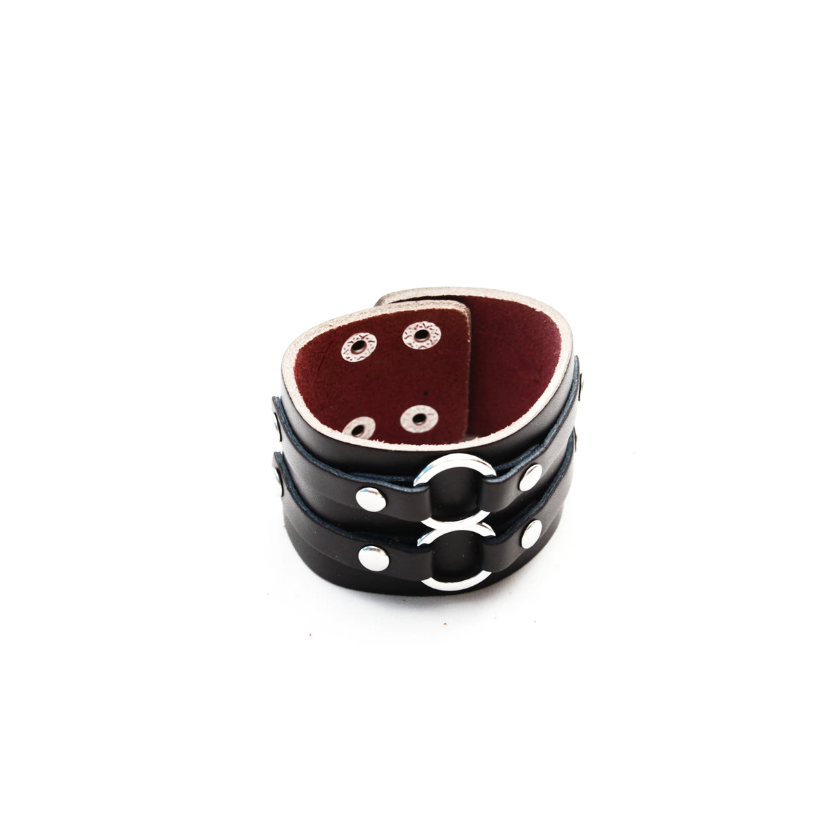 Black leather cuff bracelet with metal rings and studs, lined with red material.