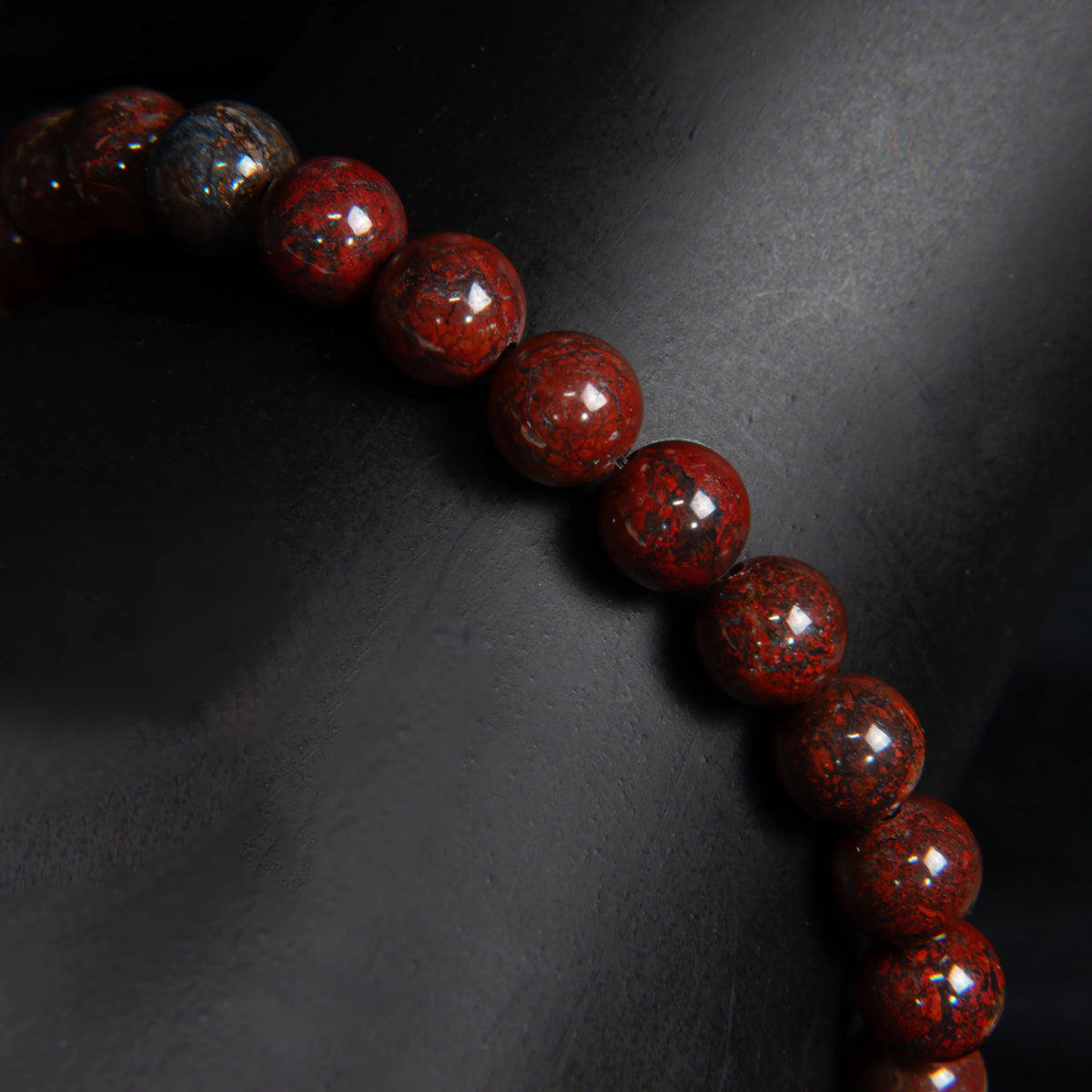 String of deep red, polished stone beads with speckled patterns.