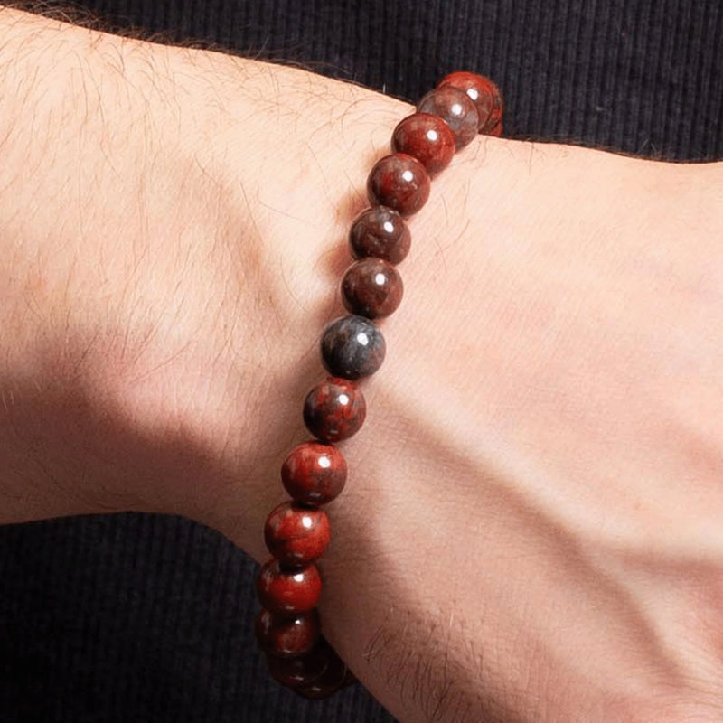 Bracelet made of polished reddish-brown beads worn on a wrist.