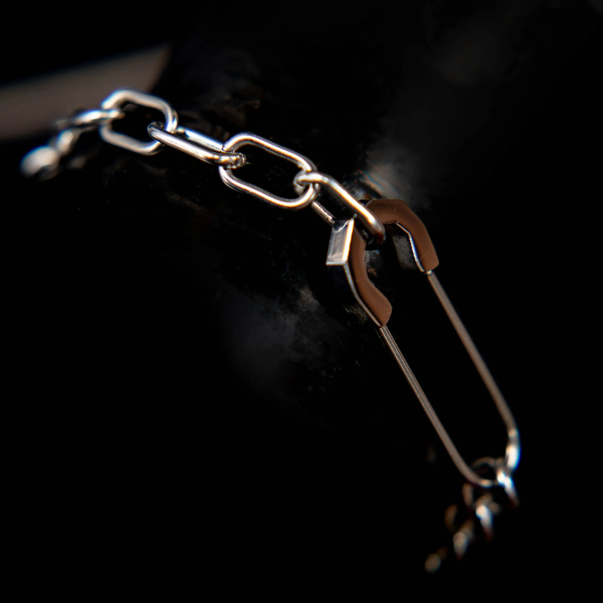 Silver chain bracelet with rectangular links and a safety pin-like clasp.