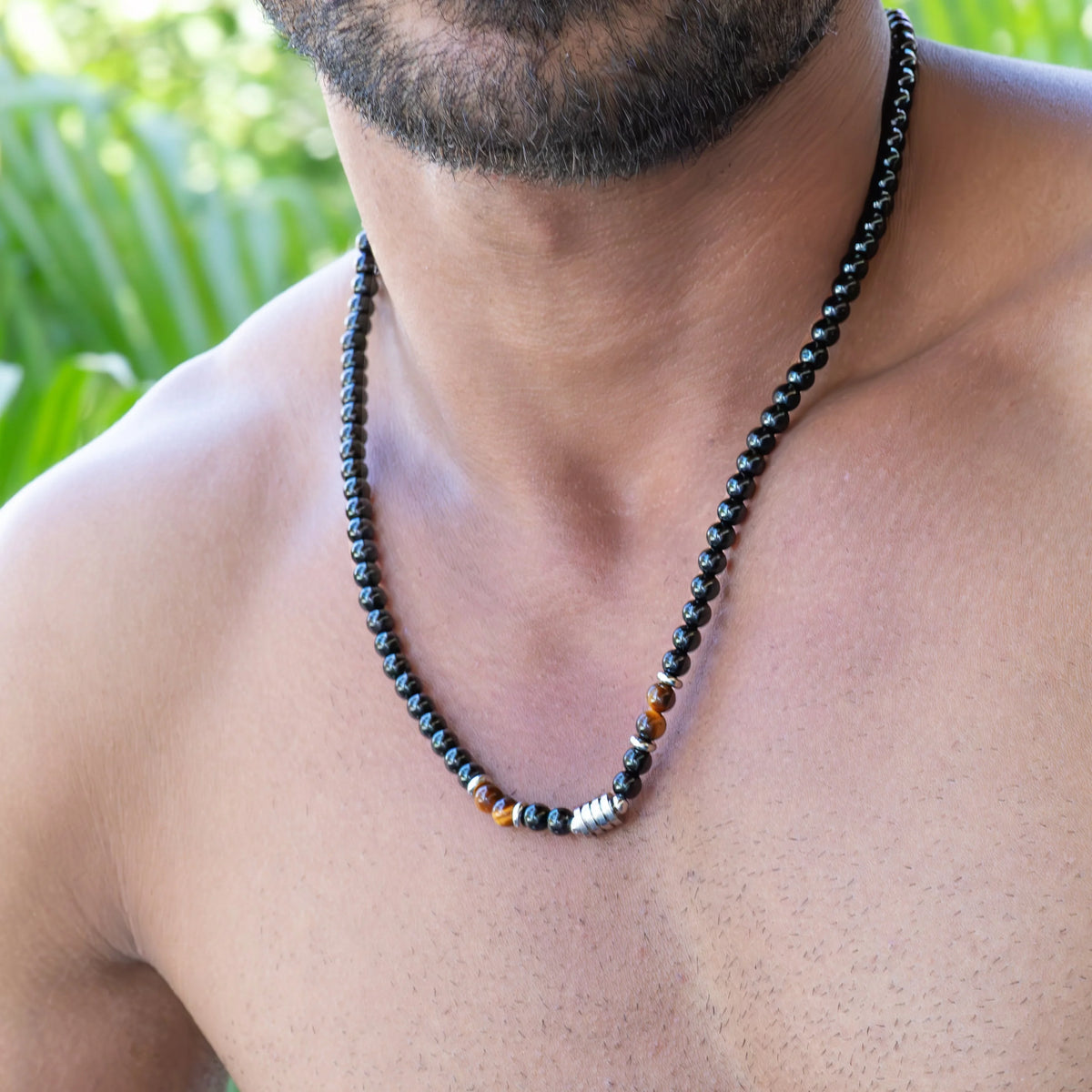 Black beaded necklace with colorful accent beads worn around a person’s neck.