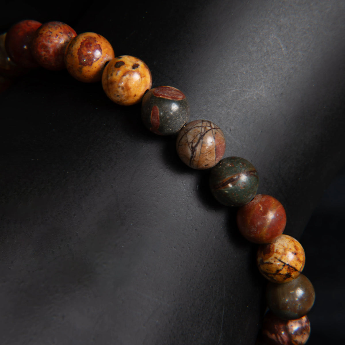 String of multicolored, polished stone or ceramic beads arranged in a curved line.