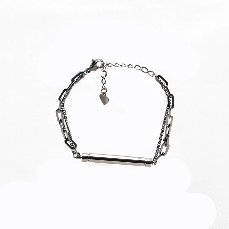 Silver chain bracelet with a cylindrical bar centerpiece and a small heart charm.