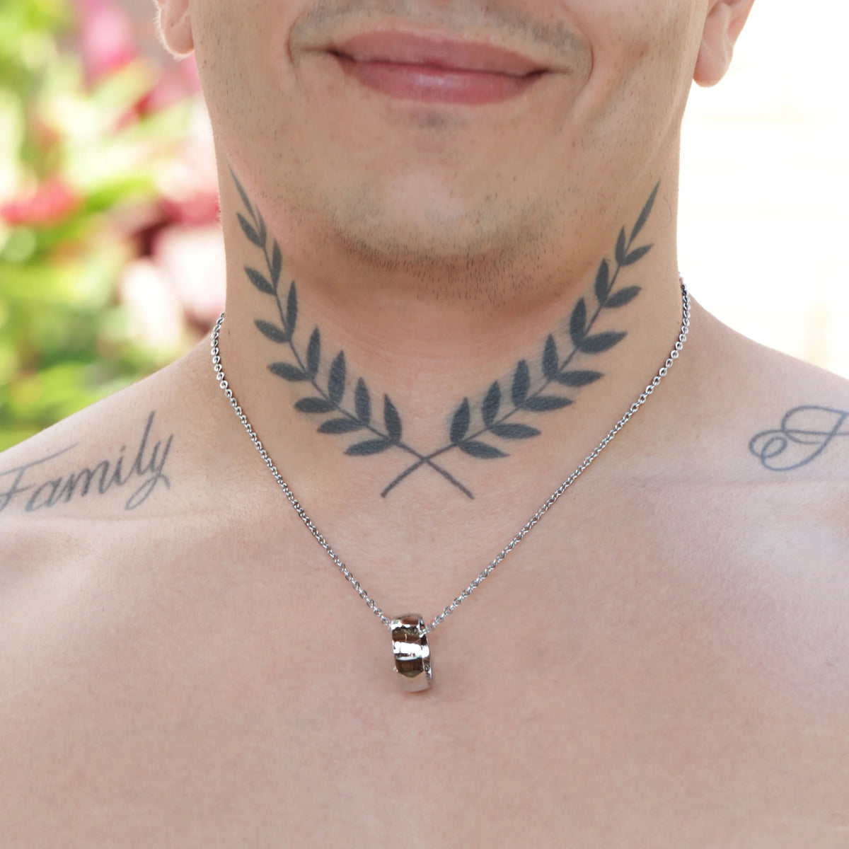 Tattoo of crossed olive branches on a person’s neck.