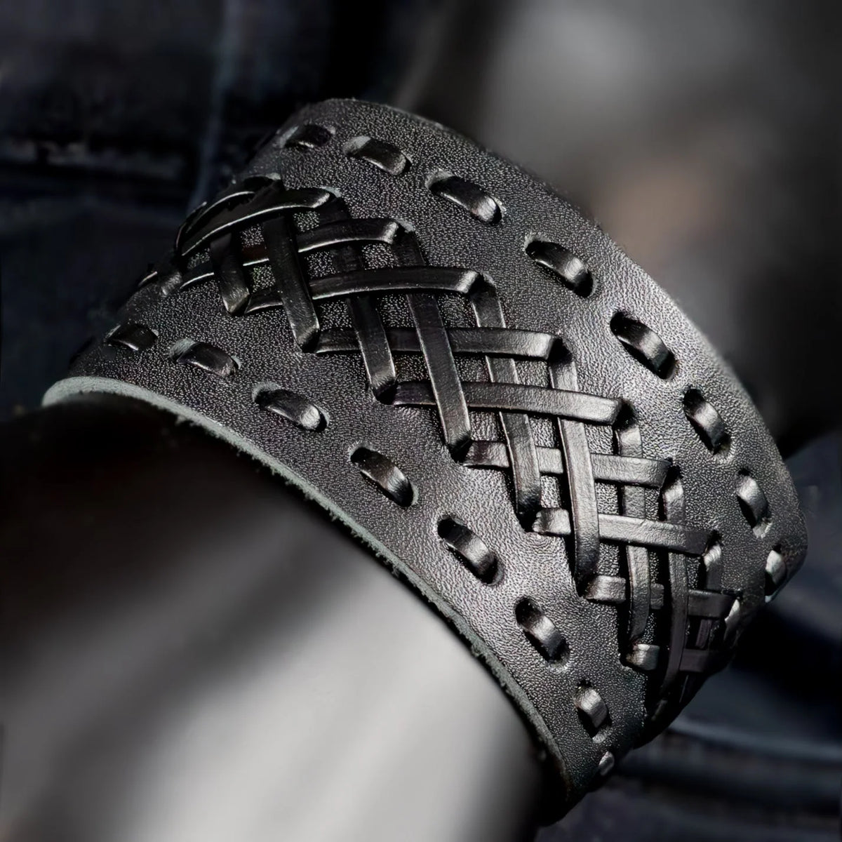 Black leather bracelet with intricate woven pattern and studded edges.