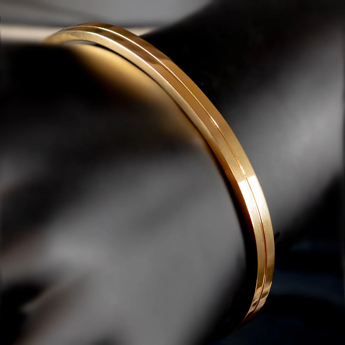 Gold bangle bracelet with a thin groove running along its circumference.