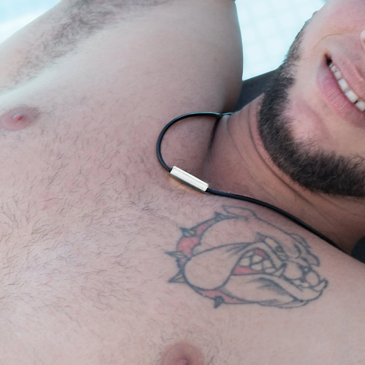 Tattoo of a cartoon-style bulldog or dog face on a person’s chest.