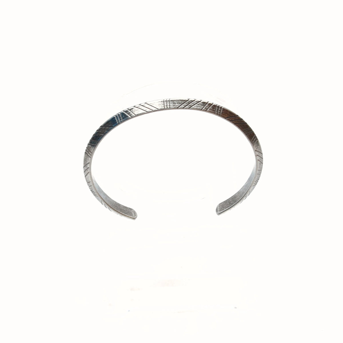 Silver cuff bracelet with etched linear patterns.