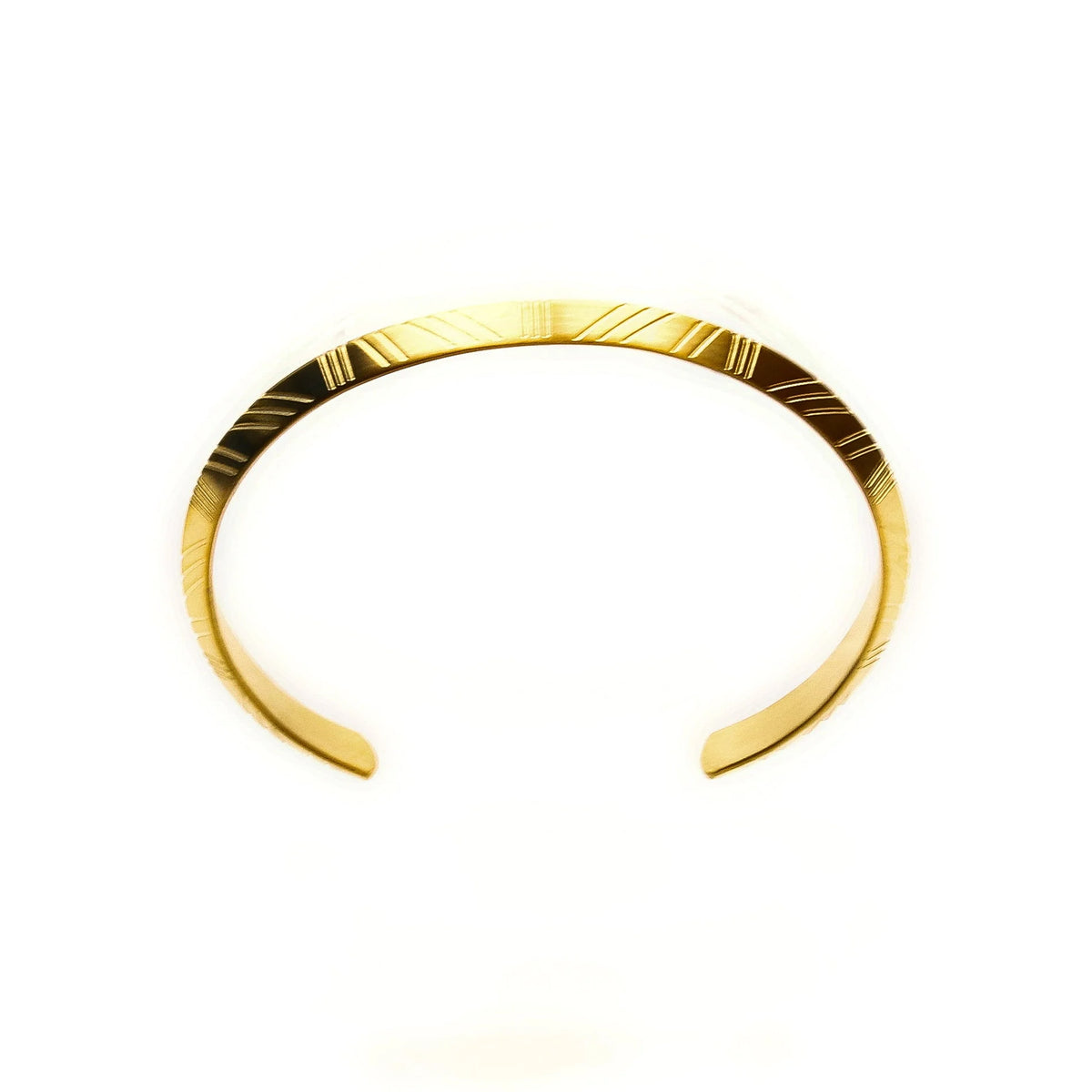 Gold cuff bracelet with engraved geometric patterns.