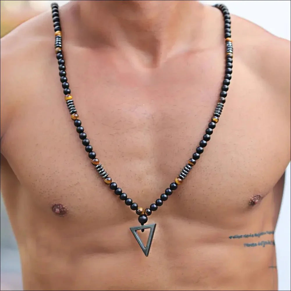 Beaded necklace with a triangular pendant worn on a person’s bare chest.