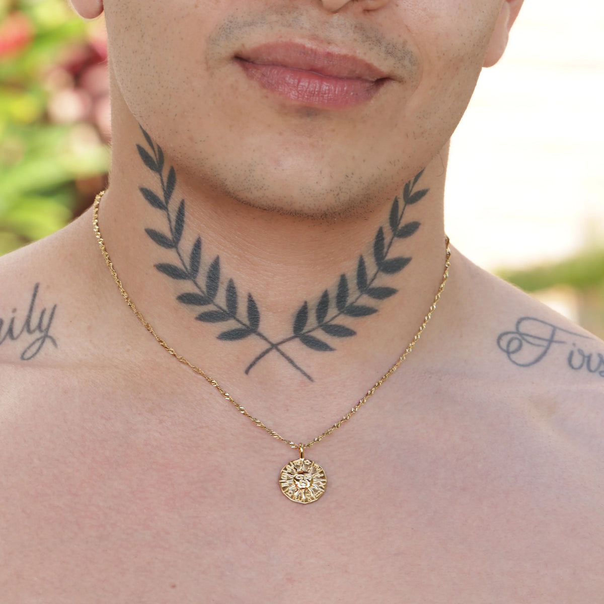 Tattoo of crossed laurel branches on a person’s neck.