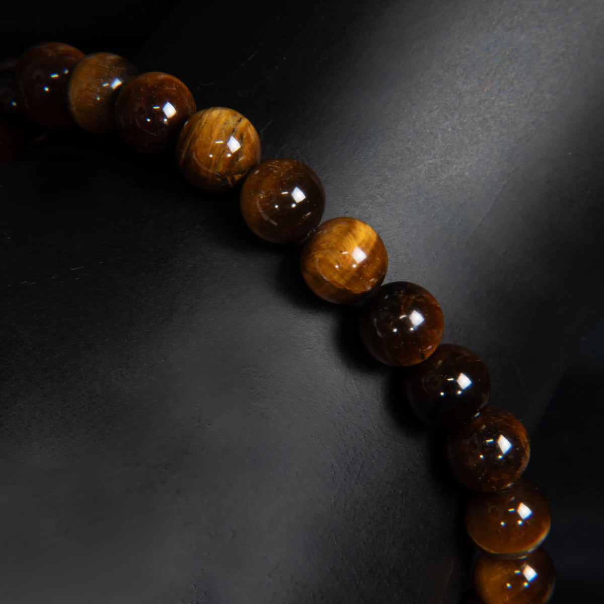 String of polished tiger’s eye beads arranged diagonally.