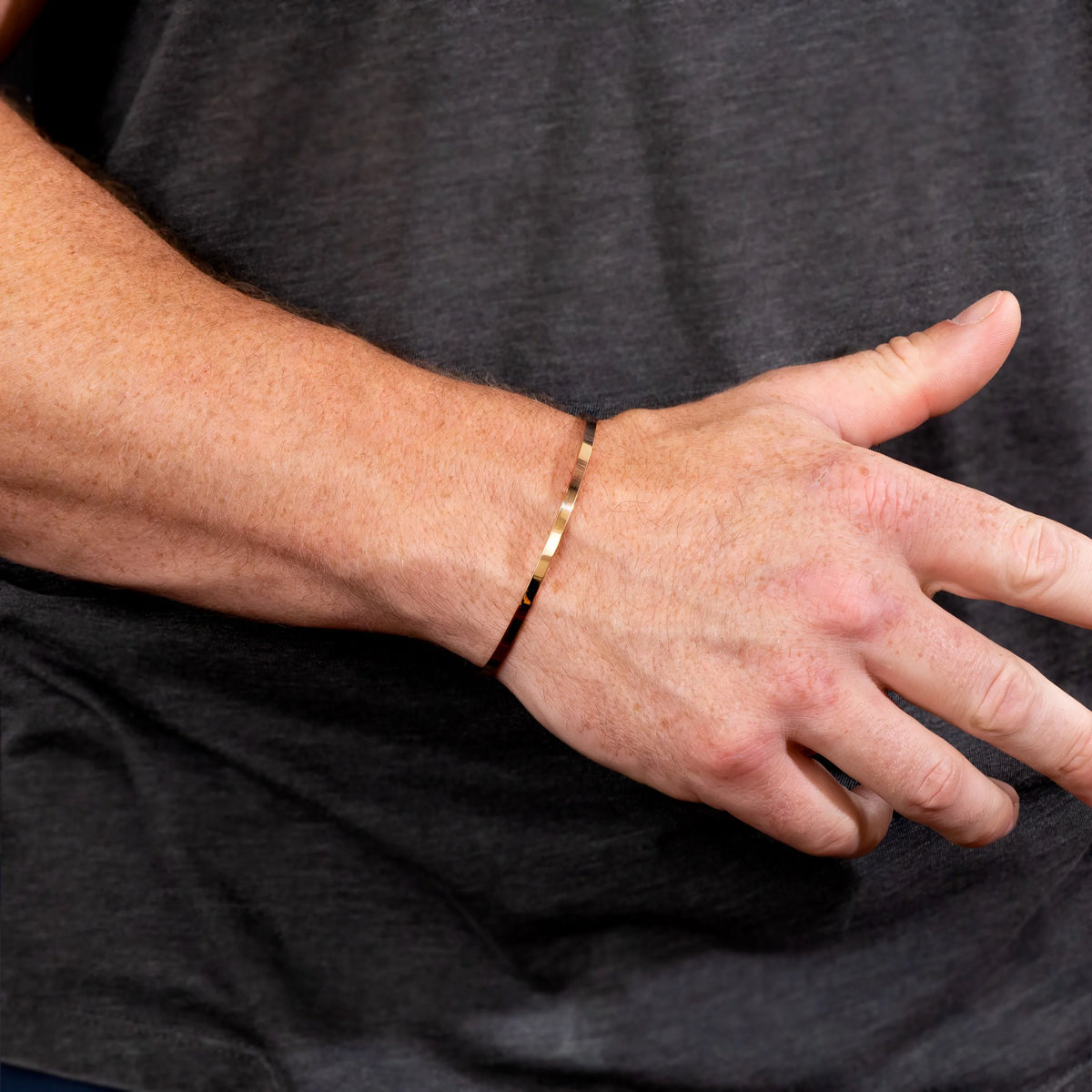 Gold bracelet worn on a wrist.