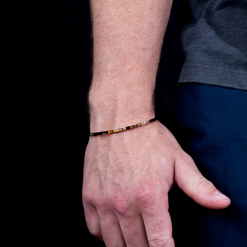 Gold bracelet worn on a wrist.