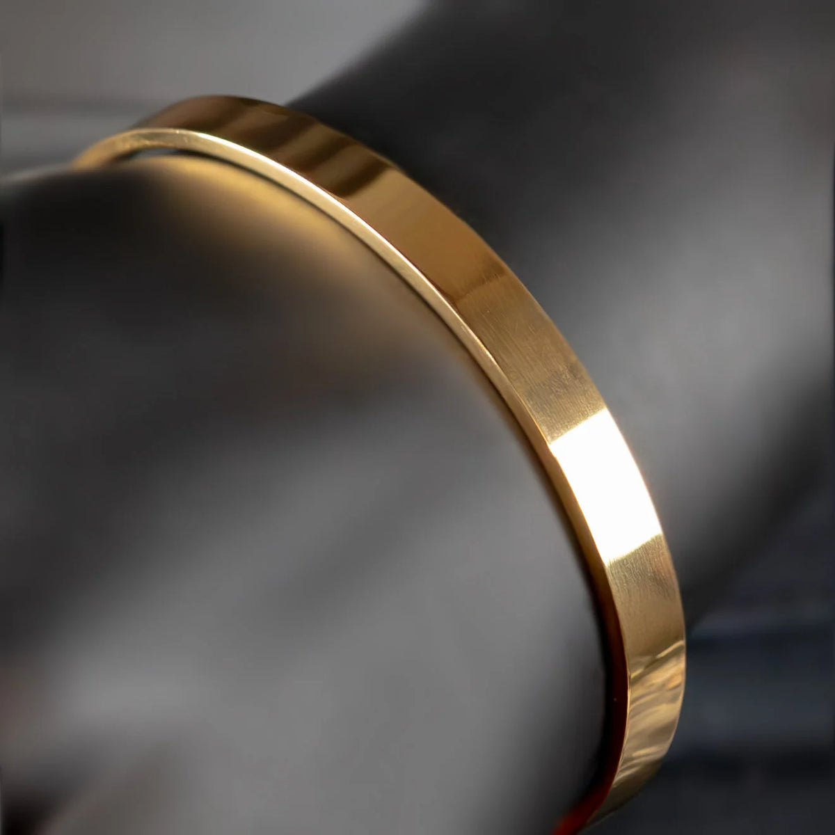 Gold-colored metal bangle or bracelet with a smooth, polished surface.