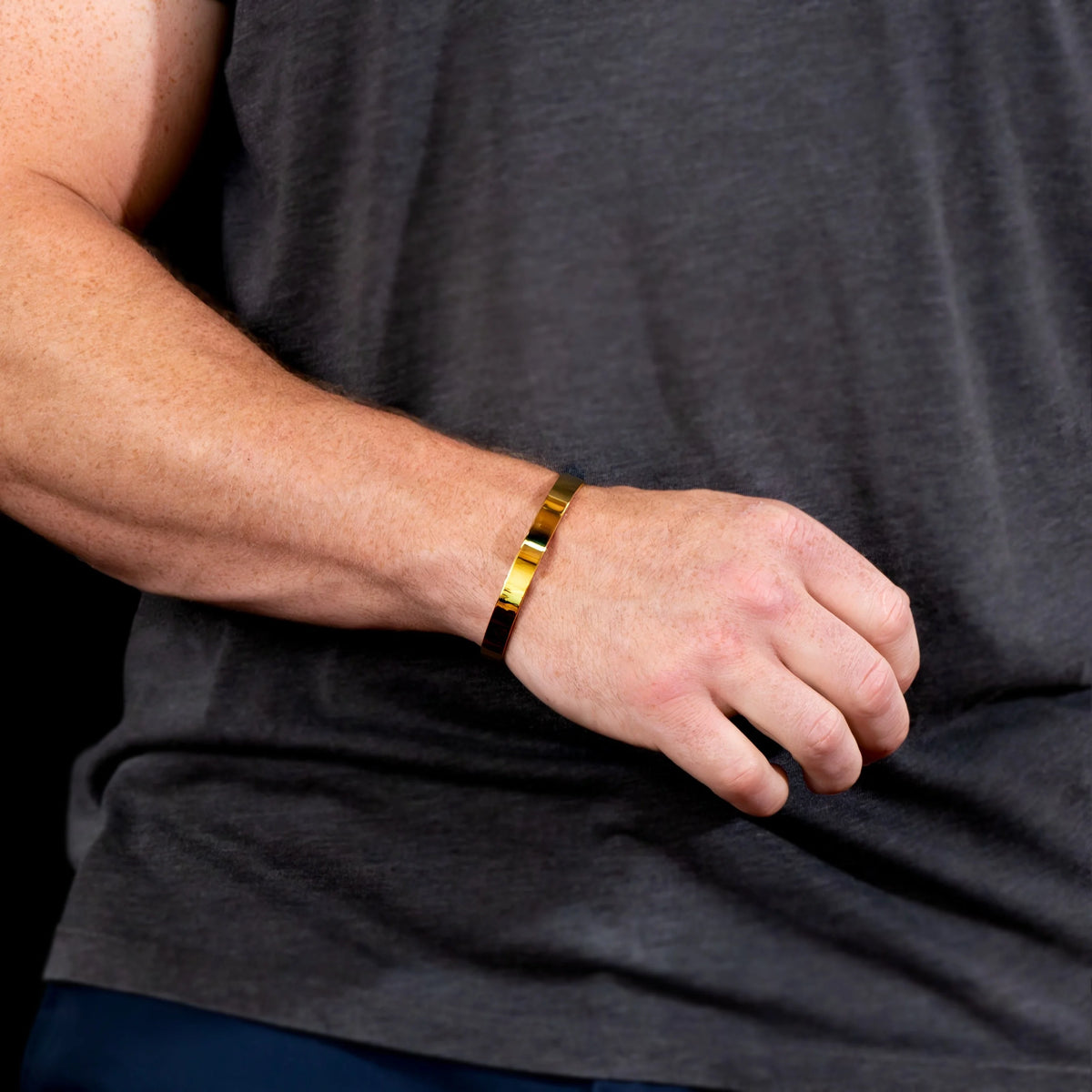 Gold-toned metal bracelet worn on a wrist.