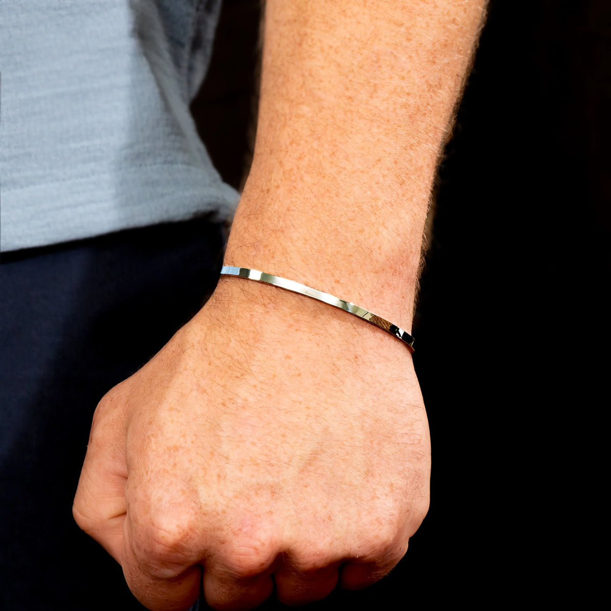 Thin silver bracelet worn on a wrist.