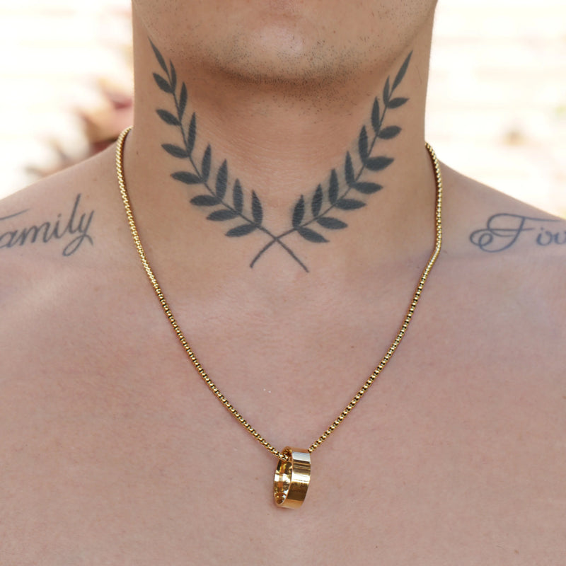 Tattoo of crossed laurel branches on a person’s neck.