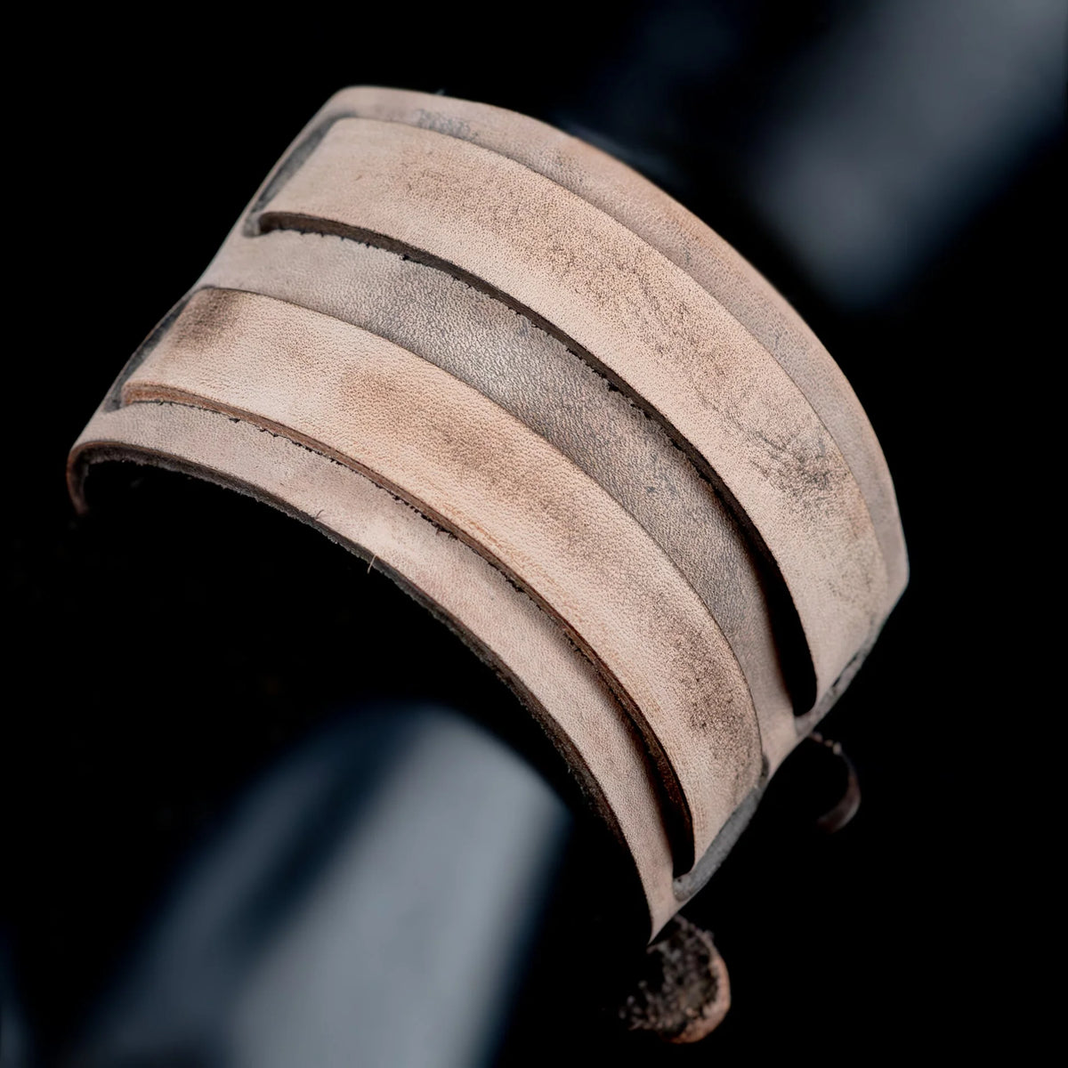 Curved leather cuff bracelet with multiple layered bands.