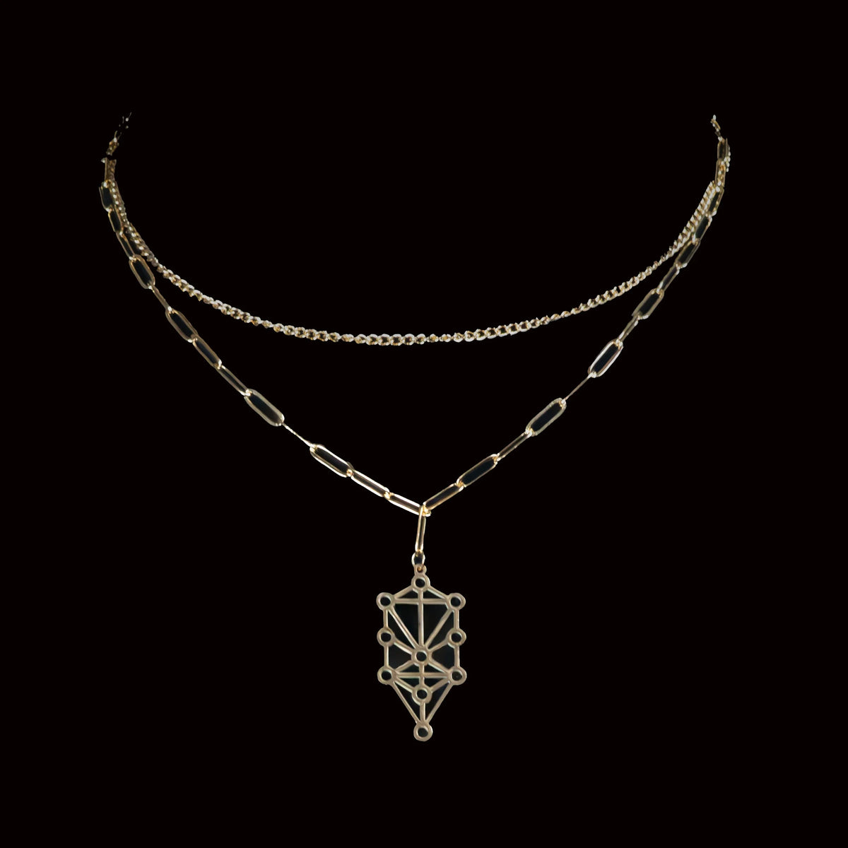 Layered gold necklace with a geometric pendant featuring the Tree of Life symbol.