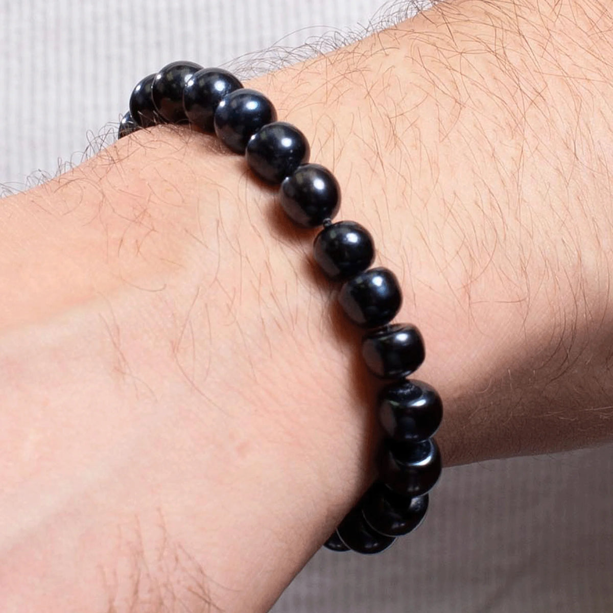 Black beaded bracelet worn on a wrist.