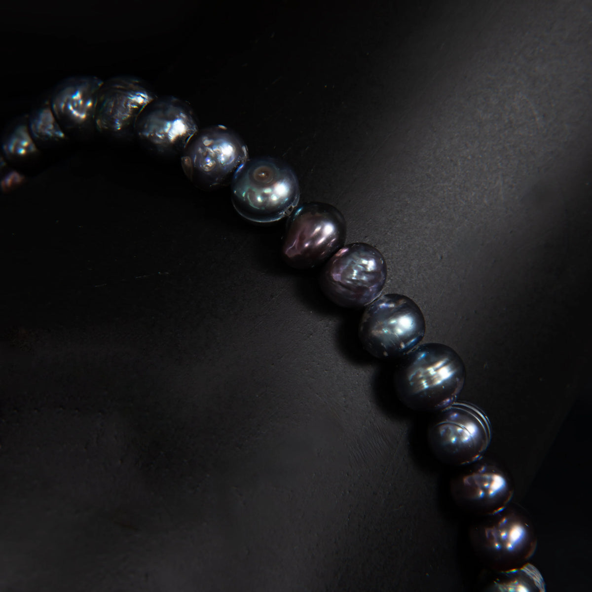 String of dark, iridescent pearls or beads curving across the frame.