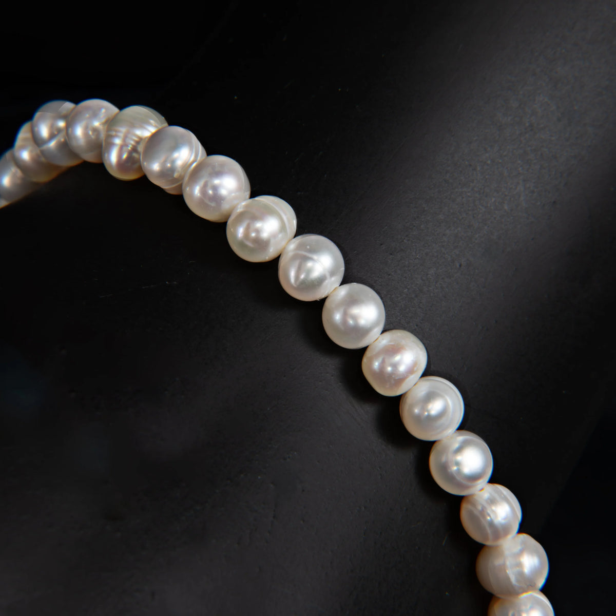 String of lustrous white pearls arranged in a curved line.