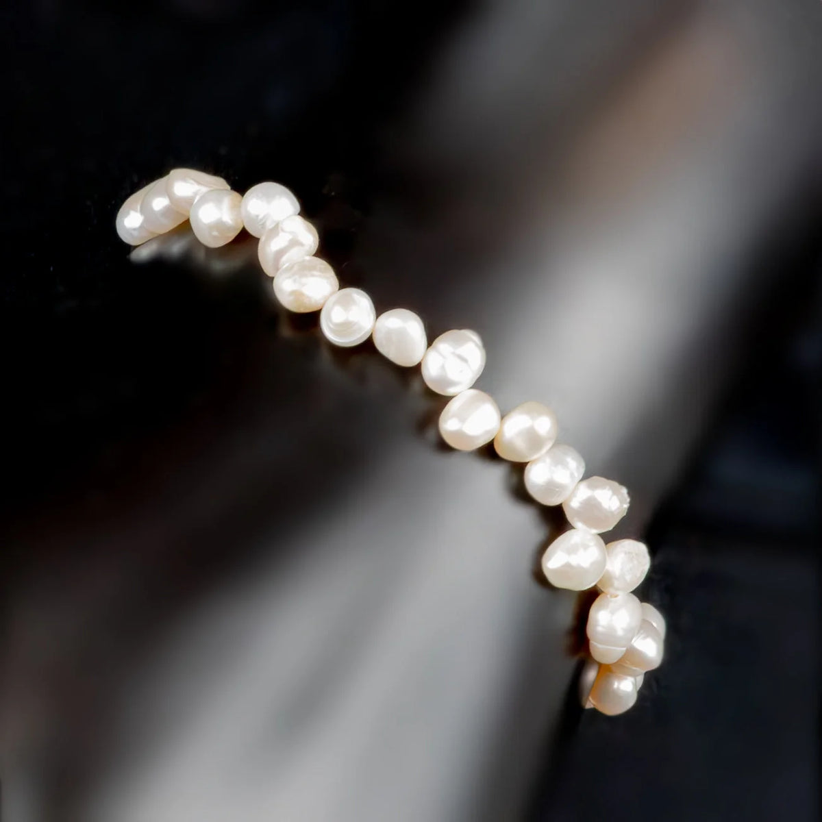 String of lustrous white pearls arranged in a curved line.