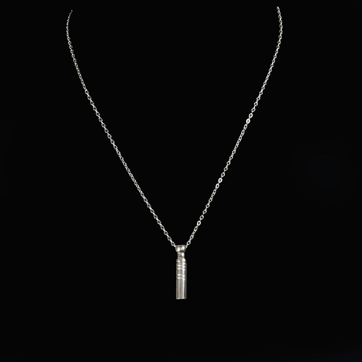 Silver necklace with a cylindrical pendant.