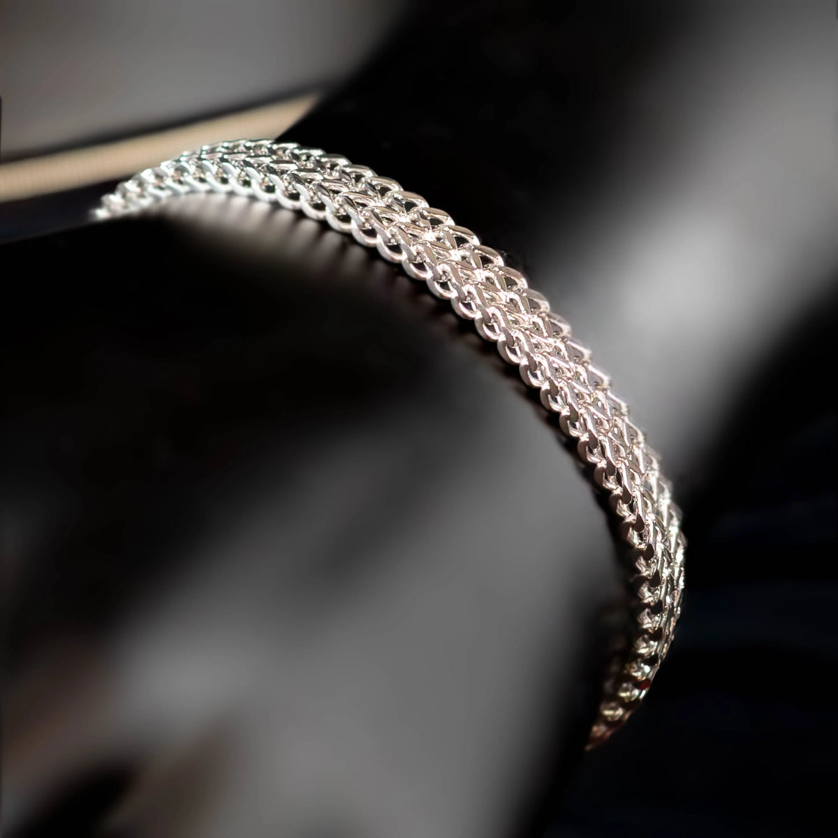 Intricately woven silver bracelet with a delicate chain-like pattern.